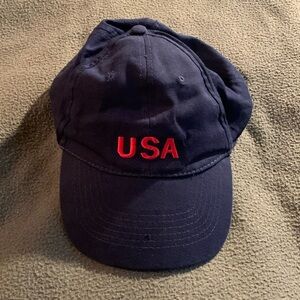 Navy hat w/ red embroidered USA.  Velcro strap in back. One size fits all